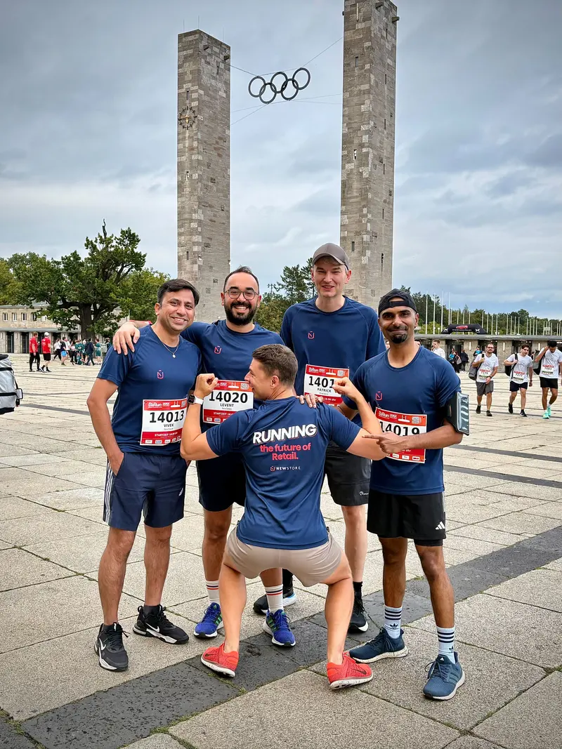 Five colleagues in NewStore running shirts and race numbers outside the Olympiastadion in Berlin