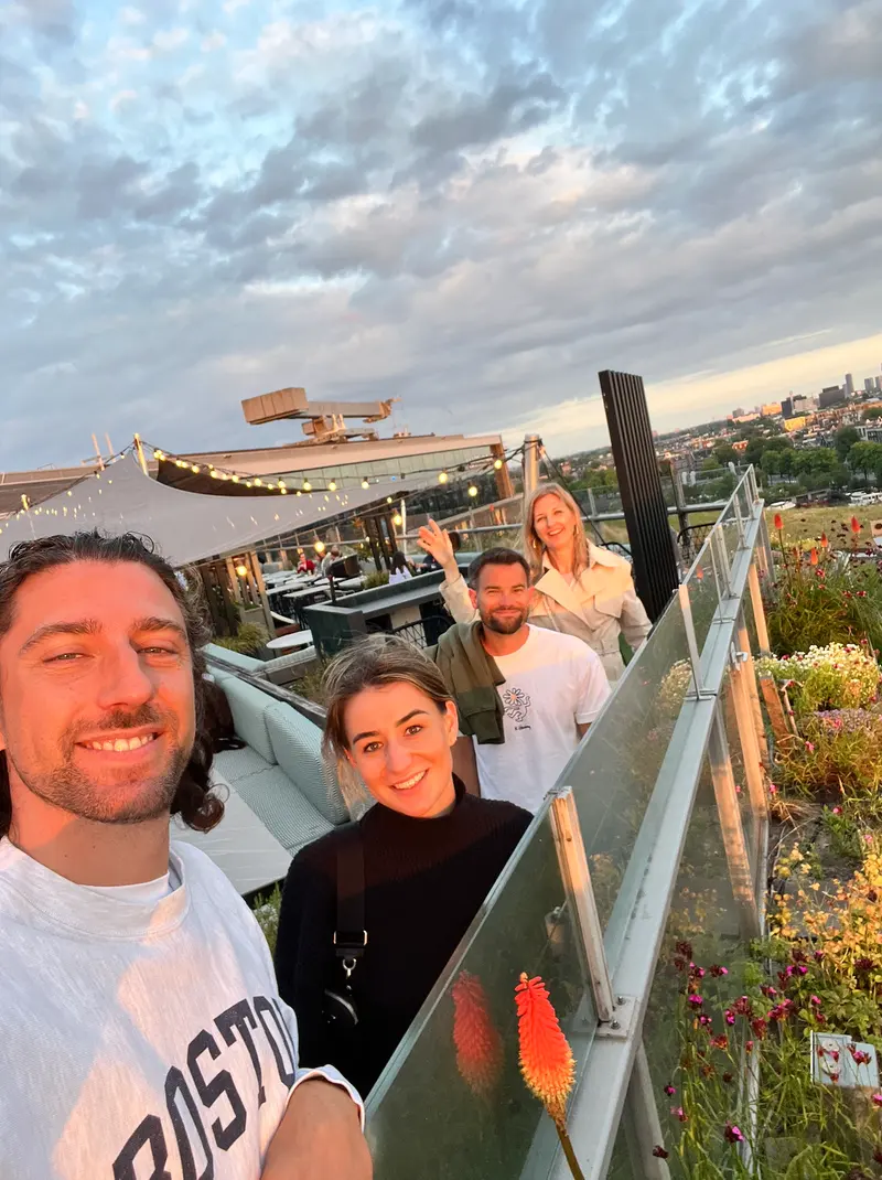 Four colleagues on a rooftop terrace at sunset